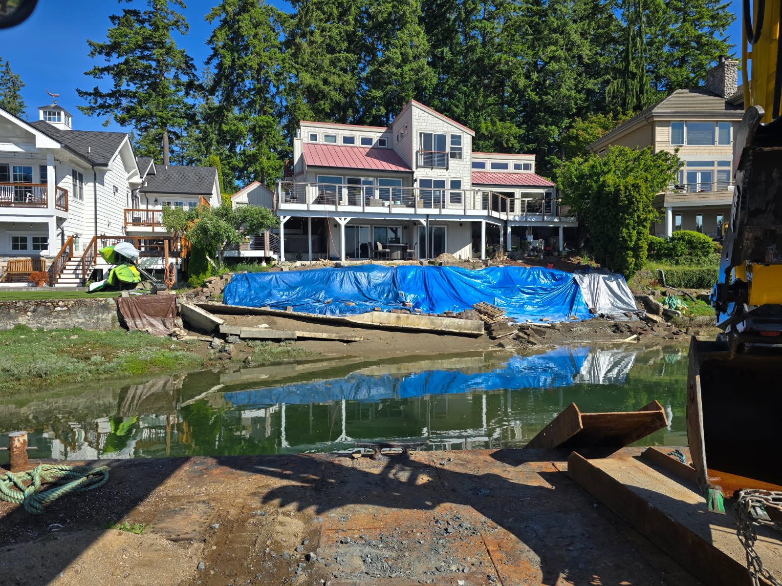 Crane operating on a marine construction barge near residential waterfront homes in the Puget Sound region